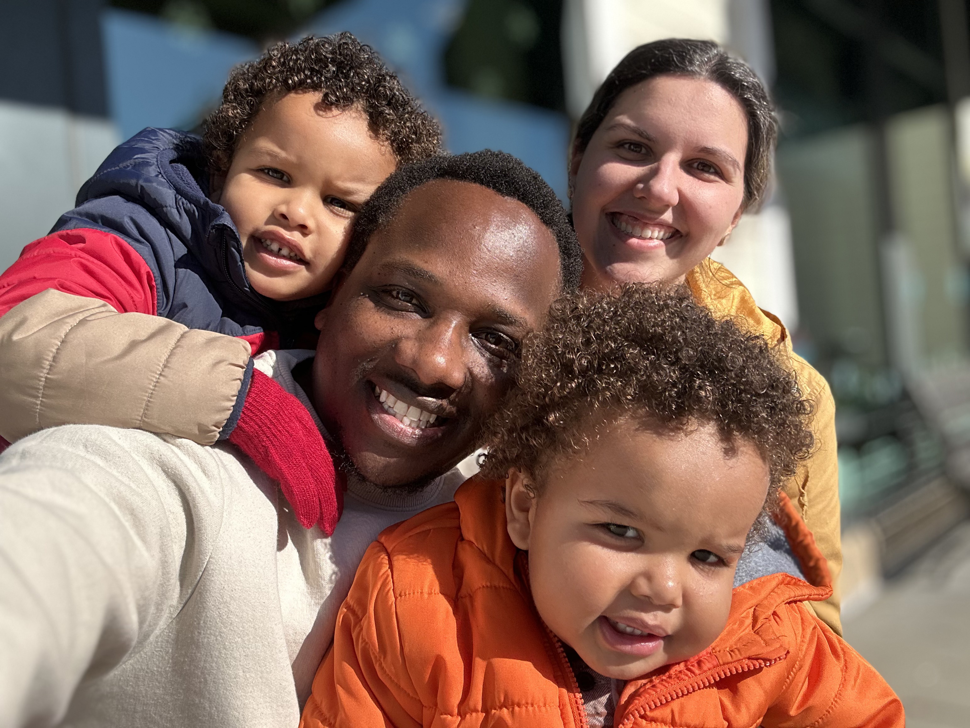 A family smiling together in a close-up outdoor portrait